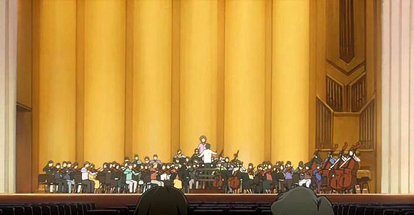 Orquestra se apresentando em um palco com fundo amarelo, com músicos tocando diversos instrumentos.